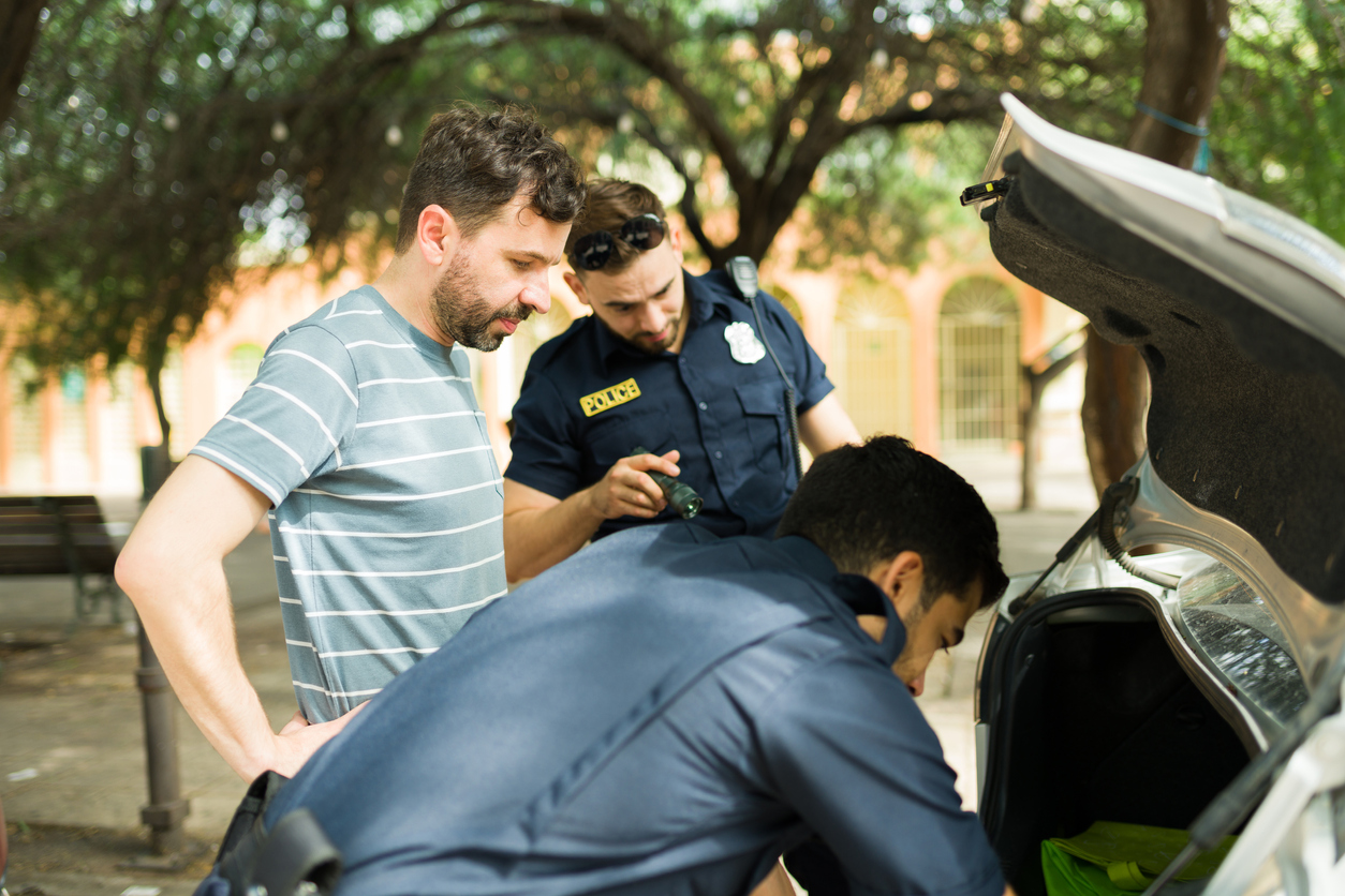 A man standing by while the police search his vehicle