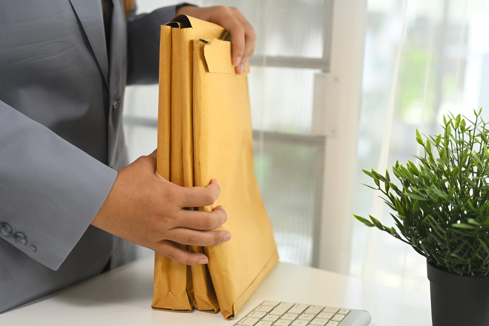 Businessperson sealing a manila envelope at an office desk