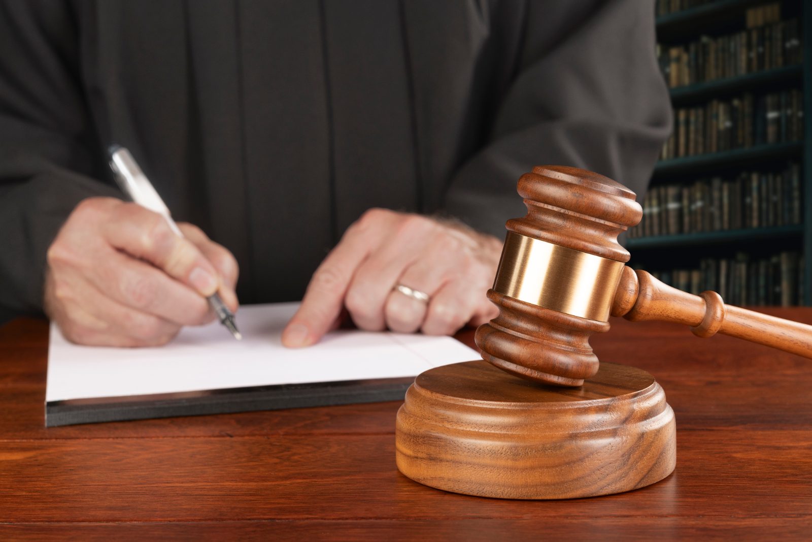 Judge writing on a document beside a wooden gavel